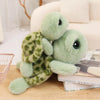 A soft green sea turtle plush toy lying on a wooden surface next to a stack of books.