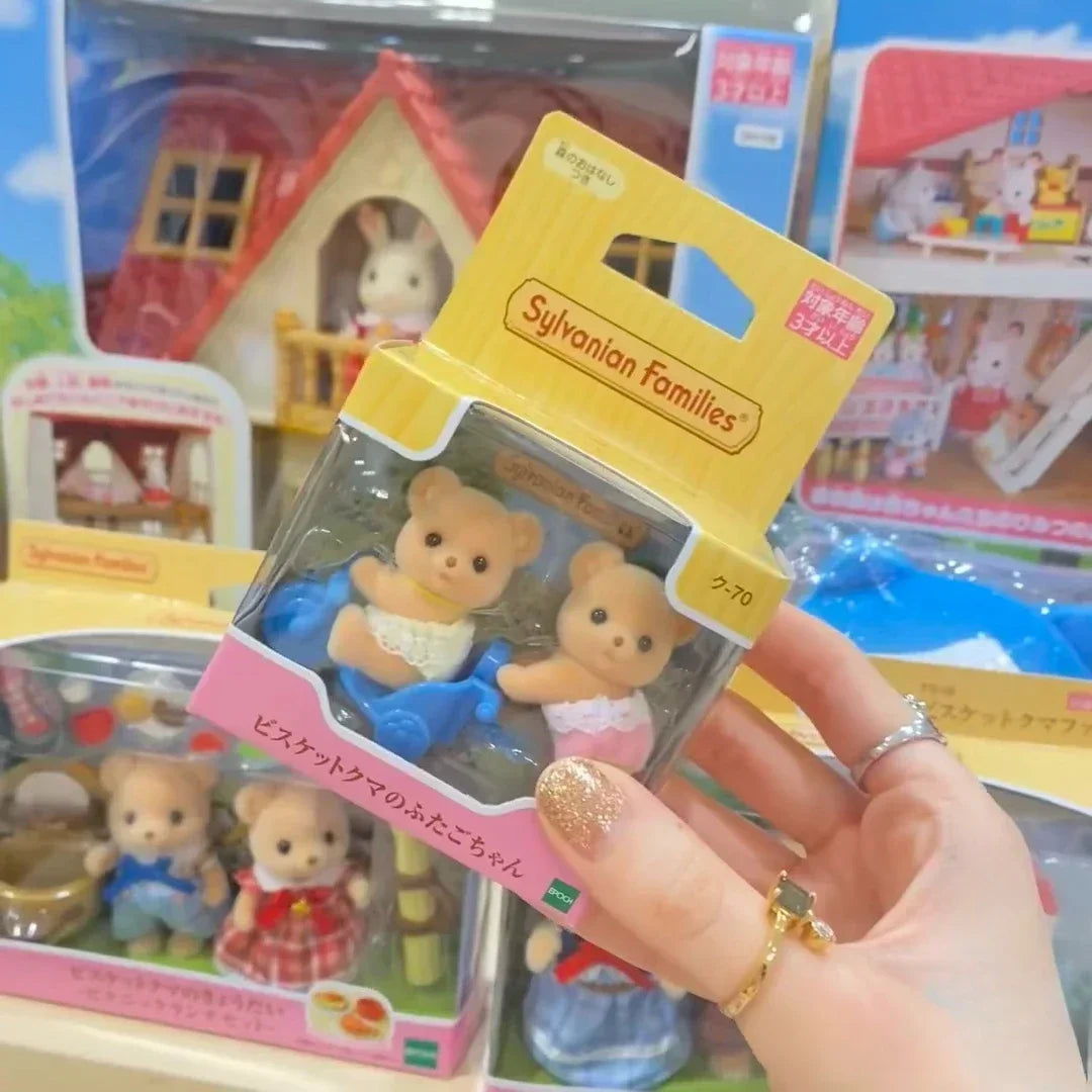 A hand holds a Sylvanian Families Cookie Bear Twins Family Set packaged in its box.