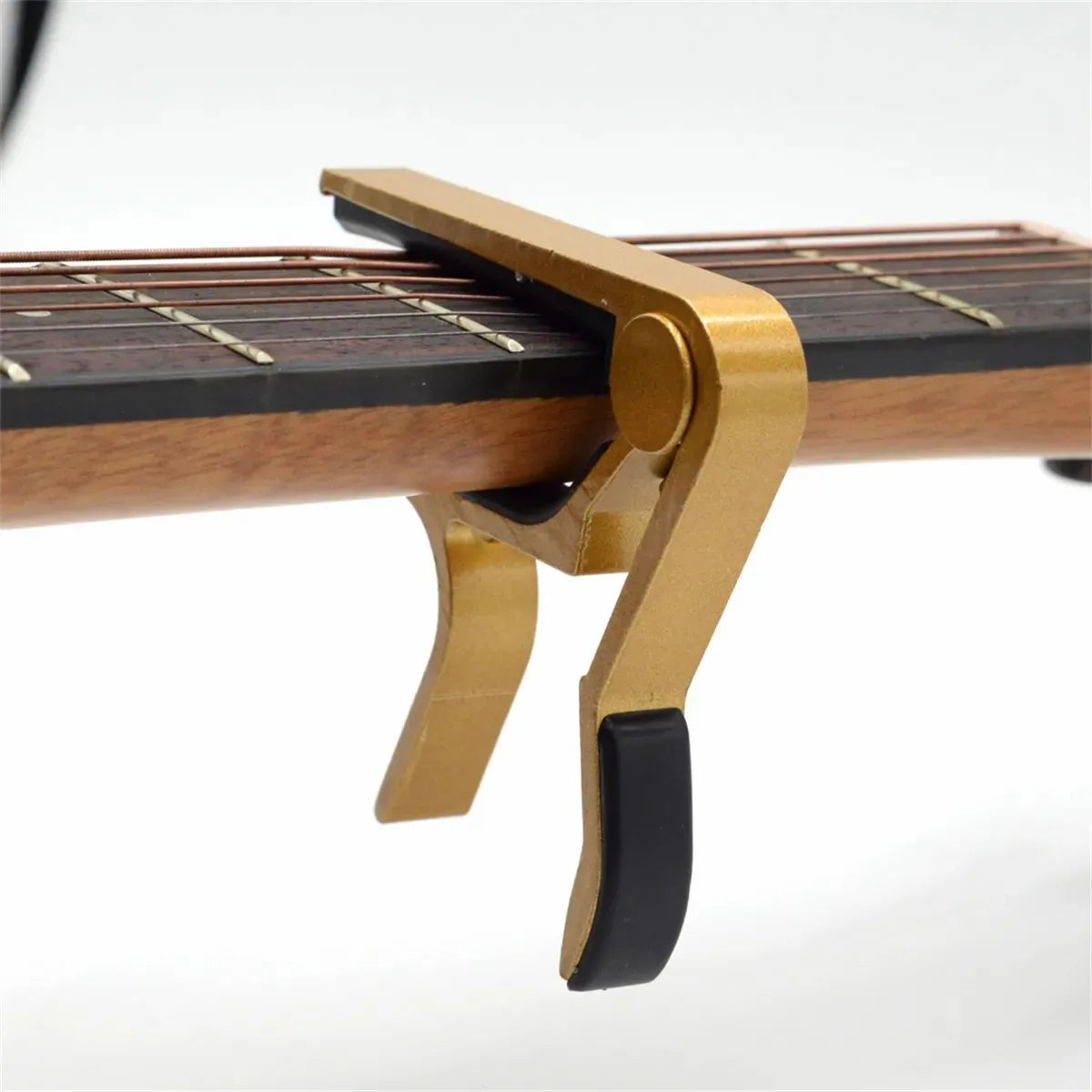 A close-up view of a brass aluminum alloy quick-change guitar capo mechanism attached to a wooden guitar neck.