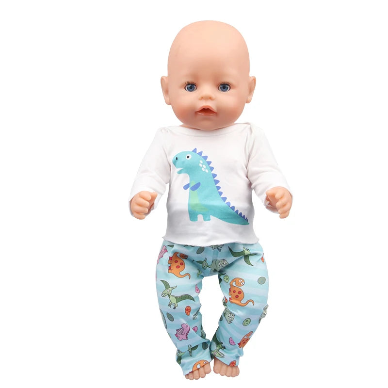A baby doll wearing a white shirt with a dinosaur graphic and patterned blue pants.