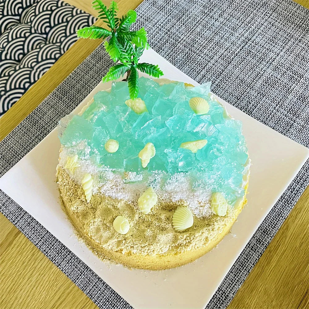 A silicone baking mold set featuring a light blue ice-like substance topped with green leaves and seashells on a white plate.