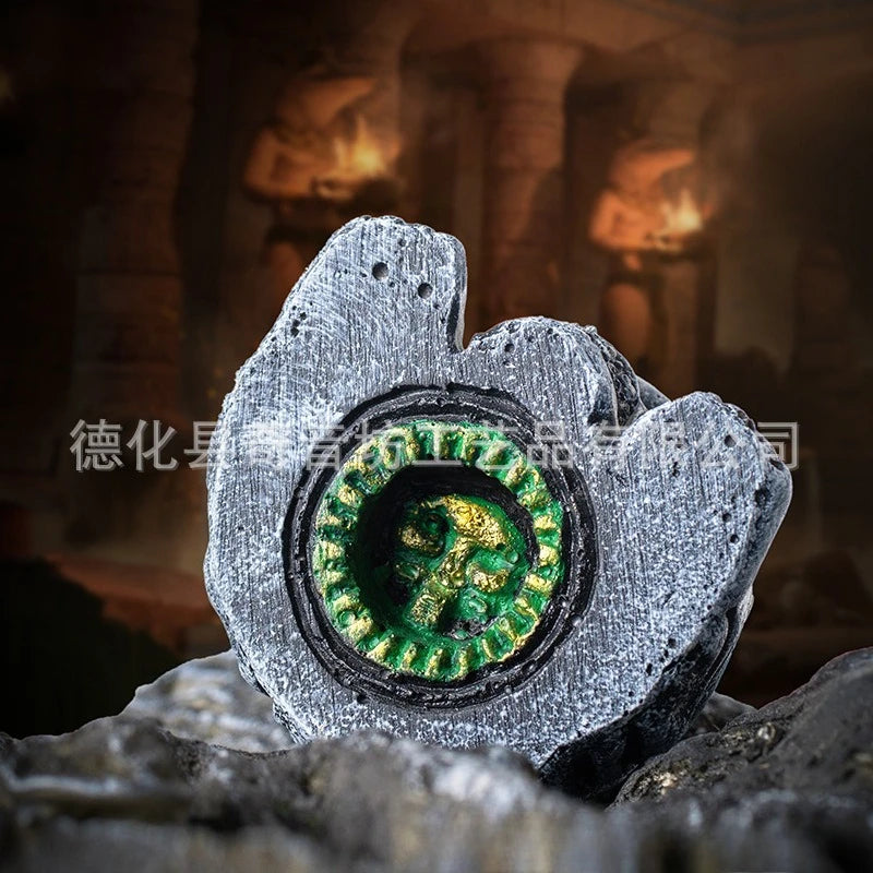 A rough stone object carved with an Aztec death whistle skull design, set against a dark, warm background.