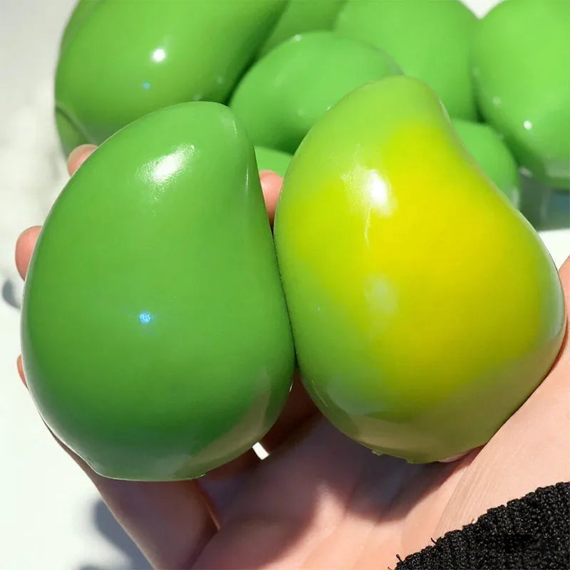 A hand holds a bright green and yellow stress ball with a translucent, glossy texture.
