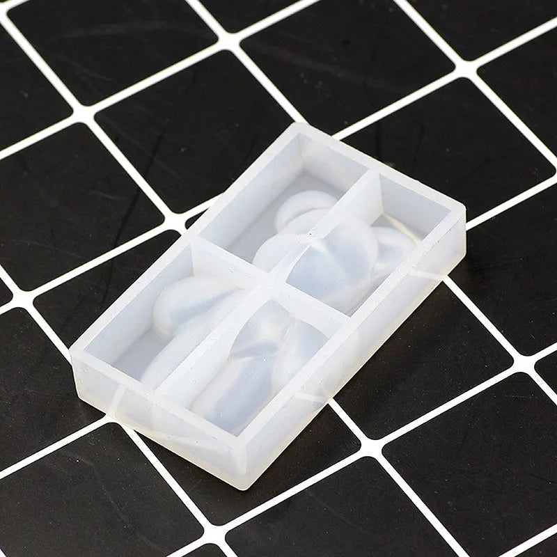 A clear plastic mold with compartments holds several white bear-shaped silicone pieces for resin jewelry and crafts.