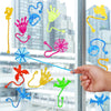 A collection of colorful, stretchy, sticky climbing toys shaped like hands, tentacles, and spider webs displayed against a gl