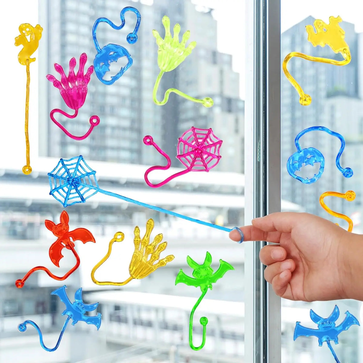 A collection of colorful, stretchy, sticky climbing toys shaped like hands, tentacles, and spider webs displayed against a gl