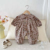 A floral print baby girl jumpsuit with a doll collar and long sleeves is displayed on a white surface.