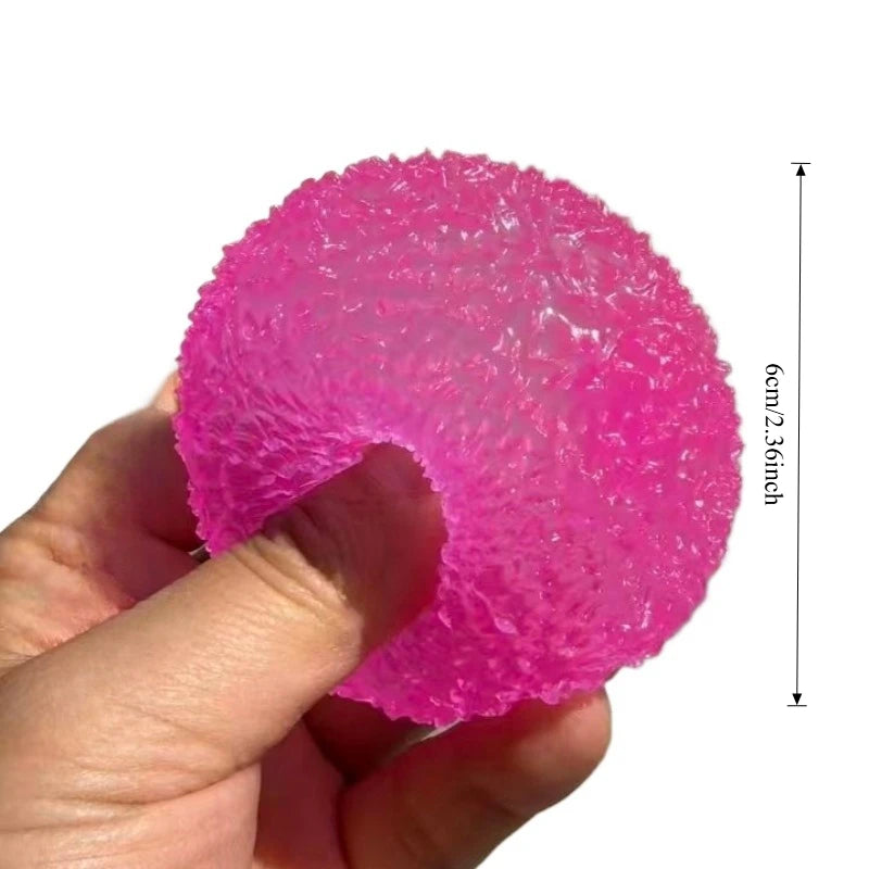 A hand holds a bright pink squishy ice ball mochi fidget toy with a slow-rebound texture.