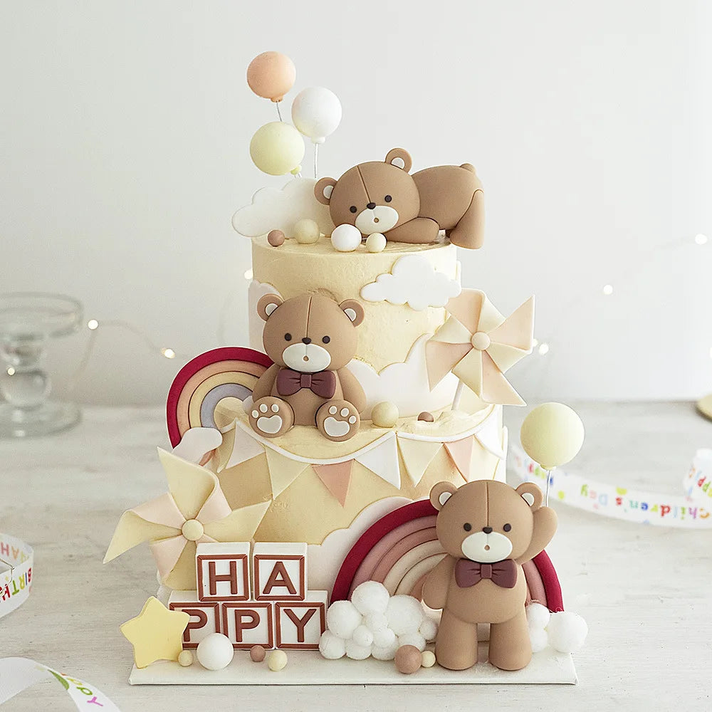 A tiered cake decorated with teddy bears and clouds, featuring soft beige and brown tones.