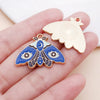Gold-toned butterfly drop charm and a gold-toned butterfly pendant resting on a hand.