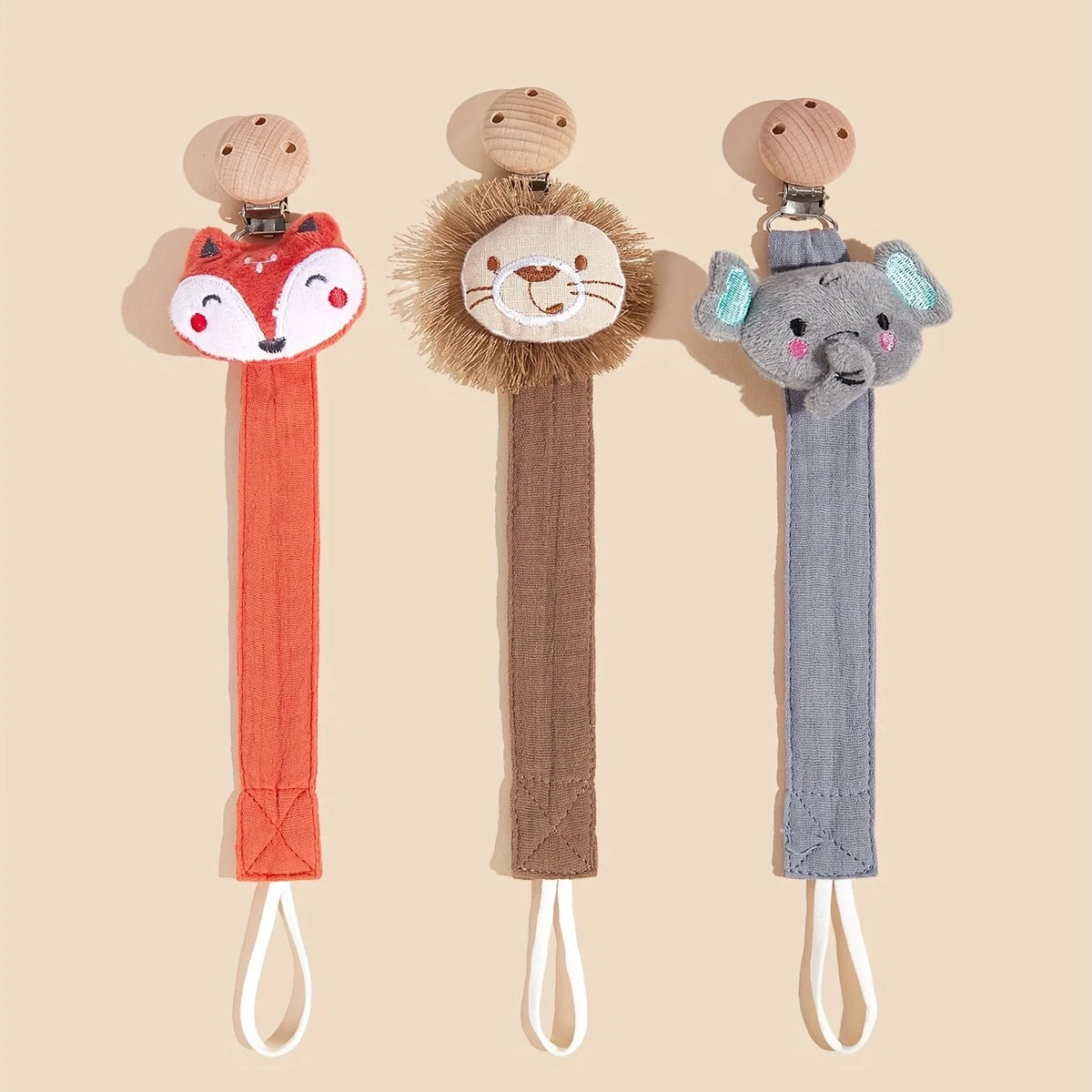 Three elephant pacifier holders in wood and fabric textures displayed against a light background.