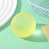 A translucent yellow football-shaped squishy fidget toy resting on a light green surface next to a wire basket.