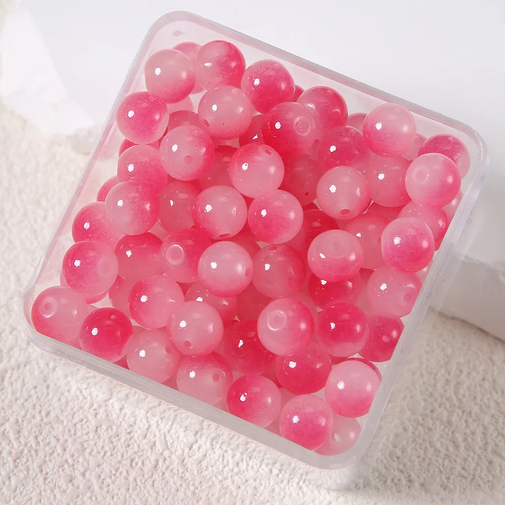 A clear plastic container filled with pink imitation jade glass beads for jewelry making