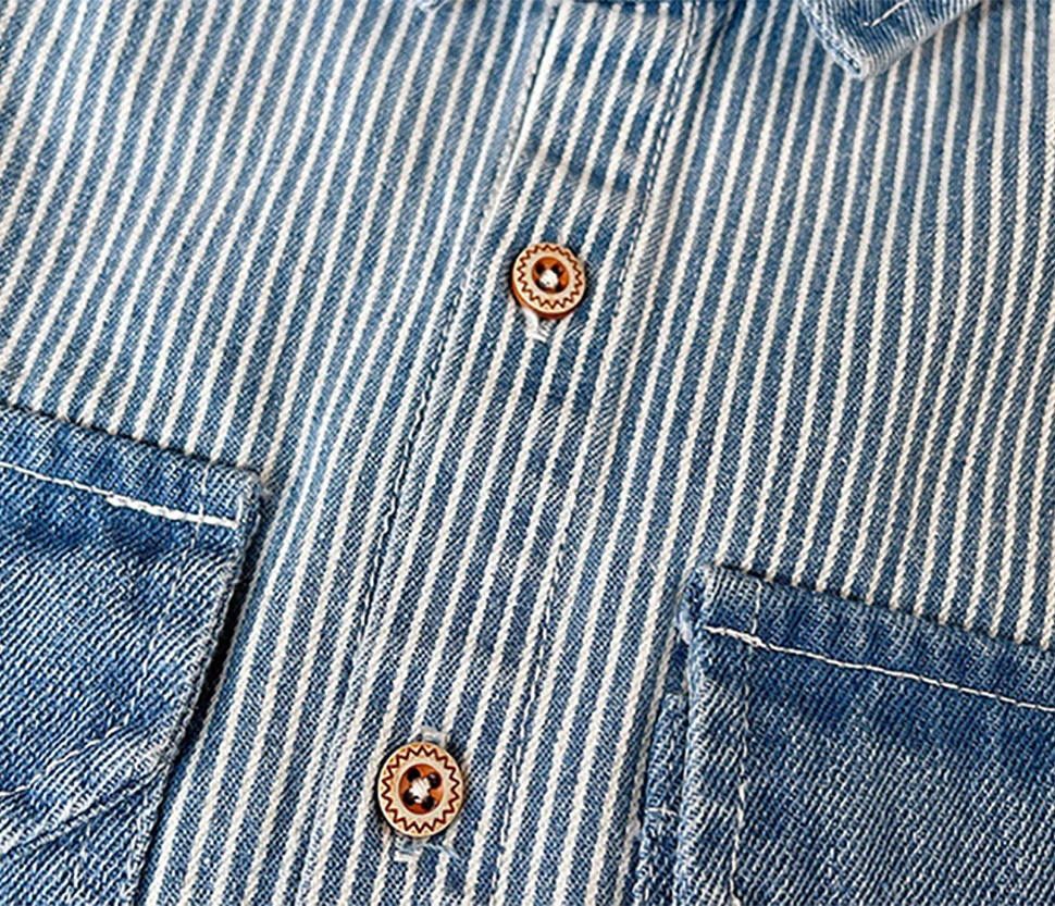 Close-up of a blue and white striped denim jacket featuring brass buttons and visible stitching details.