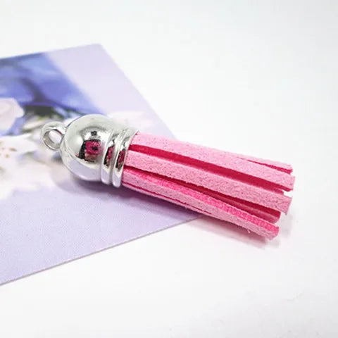 Pink velvet tassels with silver metal caps displayed on a purple card.