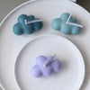 Three cloud-shaped silicone molds in teal and lavender on a white plate.