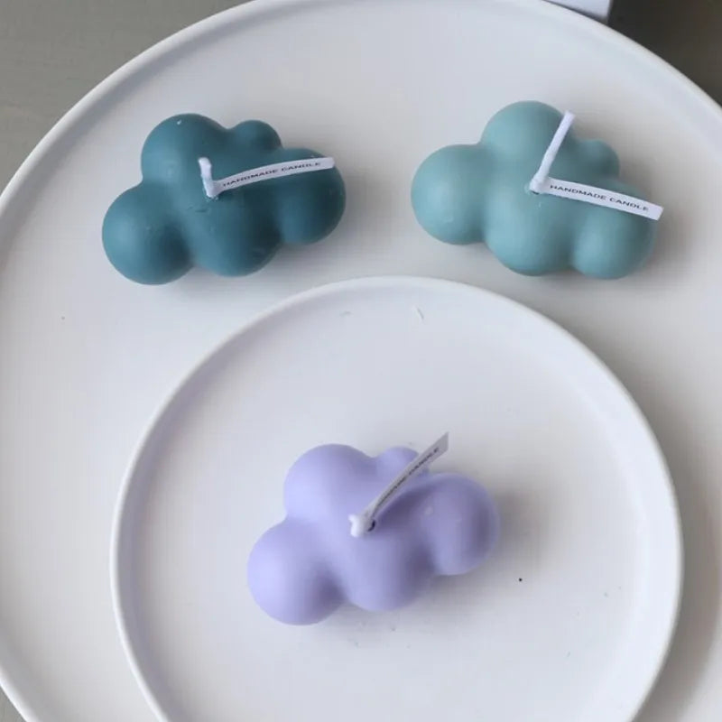 Three cloud-shaped silicone molds in teal and lavender on a white plate.
