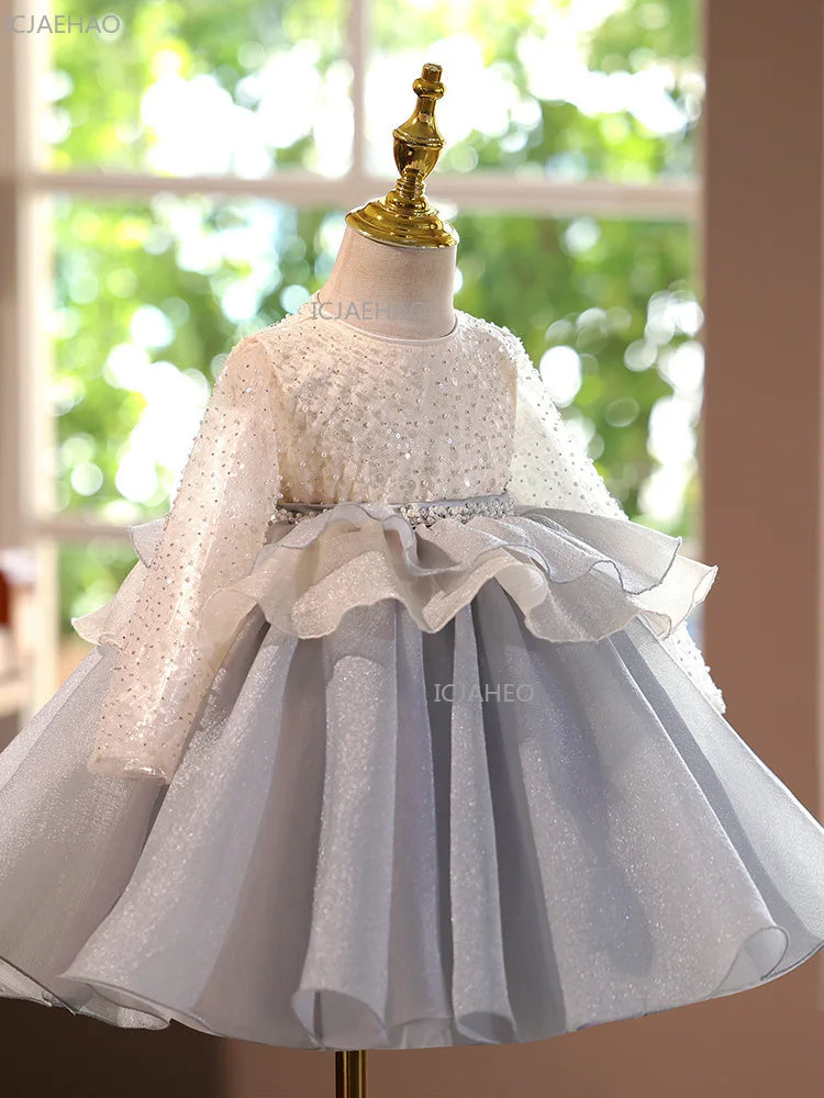 A white and gray tulle princess dress displayed on a mannequin with a gold crown.