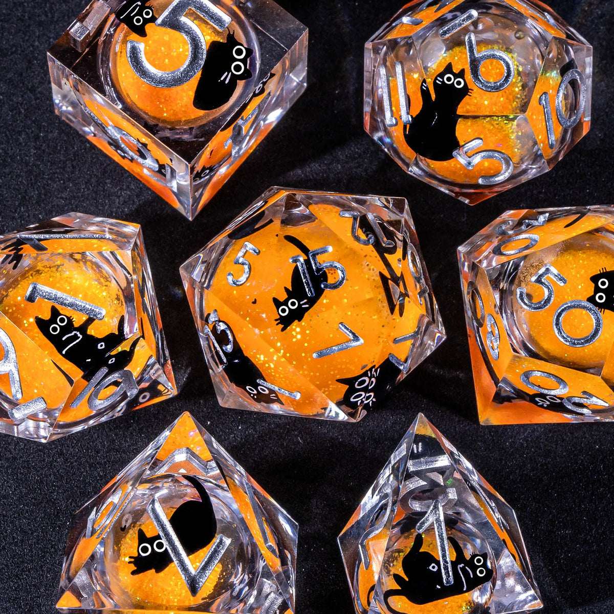 A collection of handmade liquid core resin dice set with sharp edges in various orange and clear glass shapes.