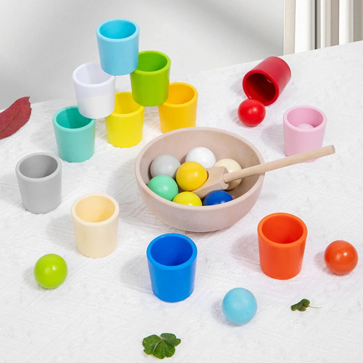 Eine Sammlung farbenfroher Plastik-Sortierbälle und Tassen in Regenbogenfarben auf einer weißen Oberfläche.