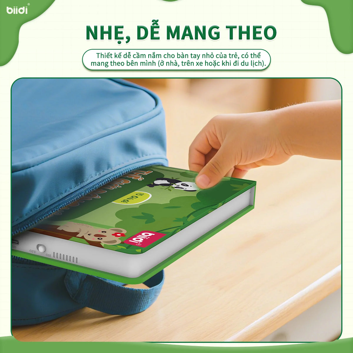 A hand is holding a green interactive talking book inside a blue storage pouch.