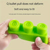 A hand holds a green silicone puzzle set with three round blocks for baby teeth practice.