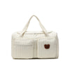 A cream-colored quilted diaper bag featuring a brown bear patch detail.
