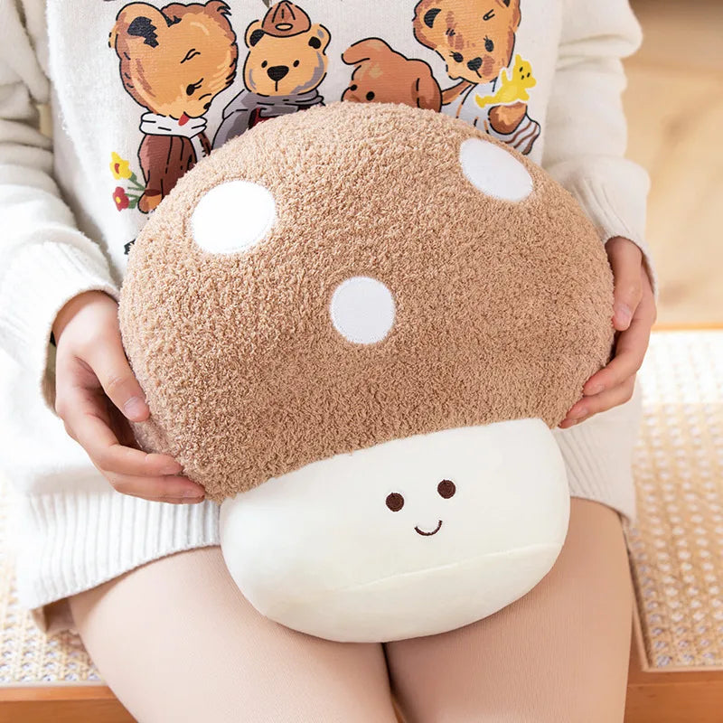 A light brown mushroom plush toy with white polka dots is held by a person wearing a cream-colored sweater.
