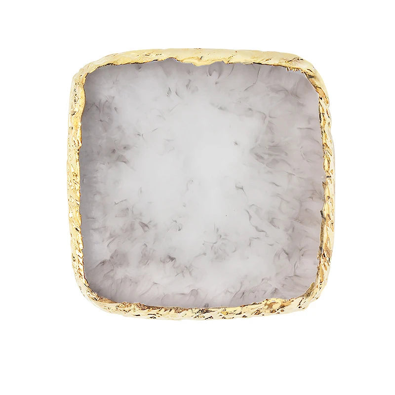 A square resin palette with a white and gray marbled surface and a gold trim.