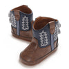 A pair of brown baby western booties with blue stitching and a soft sole.