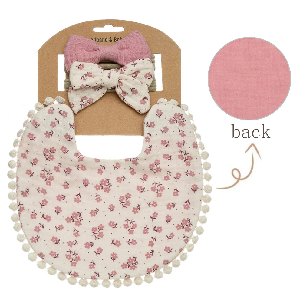 A pink floral fabric bib with a scalloped edge and a matching pink bow headband shown from the back.
