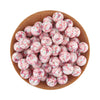 A pile of pink and white floral silicone beads in a wooden bowl for jewelry making