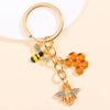 Gold-toned enamel flower keychain featuring a bee charm and a daisy design.