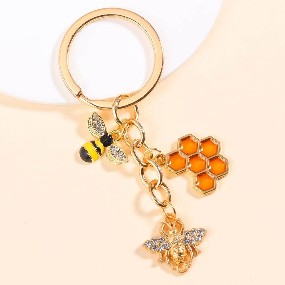 Gold-toned enamel flower keychain featuring a bee charm and a daisy design.