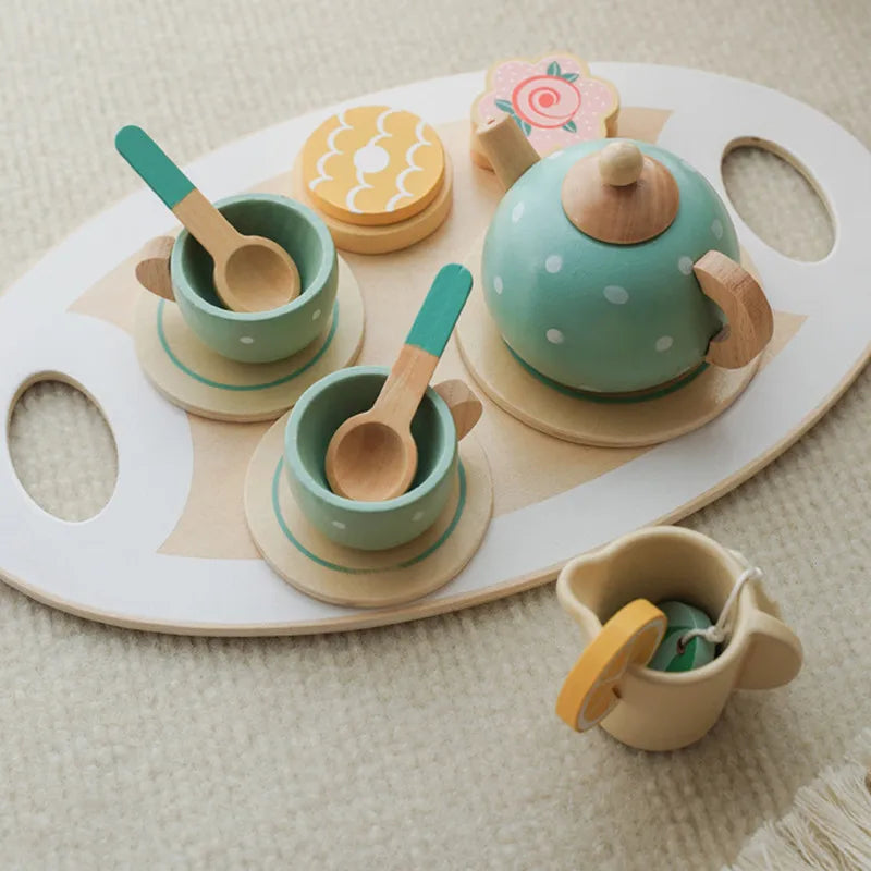 A wooden pretend play tea party set featuring a teapot, cups, and spoons in pastel green and natural wood tones.