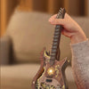 A hand holds a wooden miniature guitar model kit, showing the detailed buildable puzzle craft for music lovers.