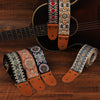 A collection of embroidered guitar straps featuring various patterns and leather ends laid out on a wooden surface.