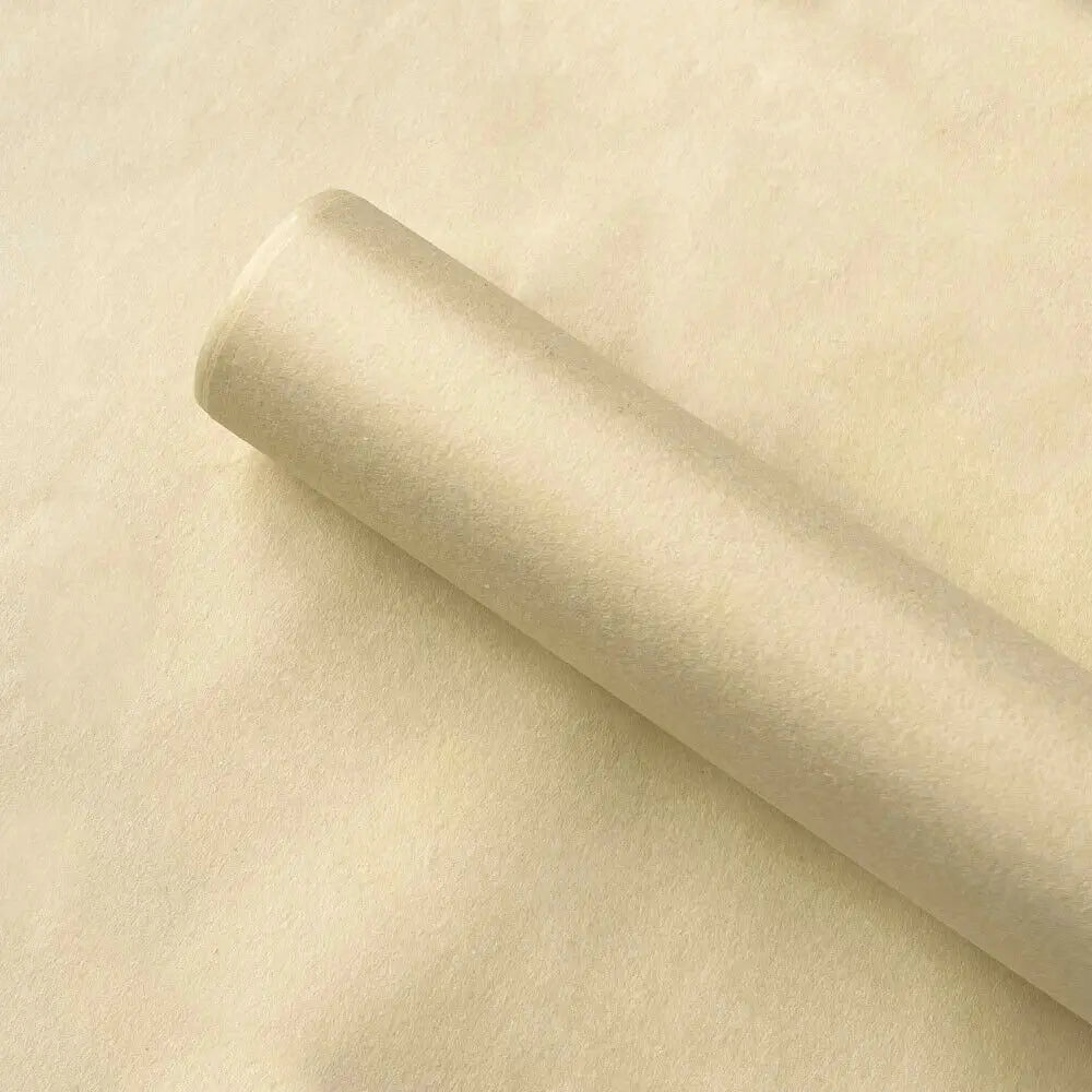 A roll of translucent tissue paper sheets lying on a light beige surface.
