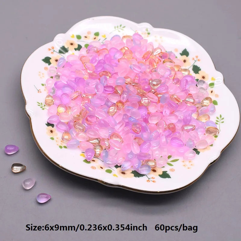 A plate filled with pink and purple water drop glass beads for jewelry making