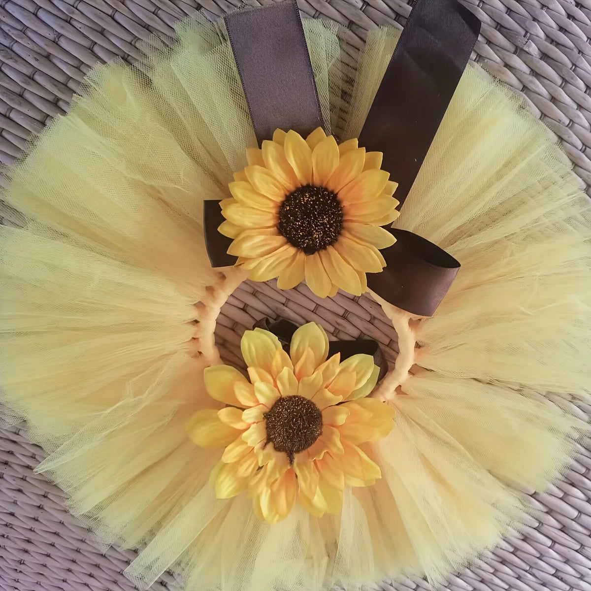 A yellow tulle sunflower baby tutu skirt and headdress set with a large fabric flower centerpiece.