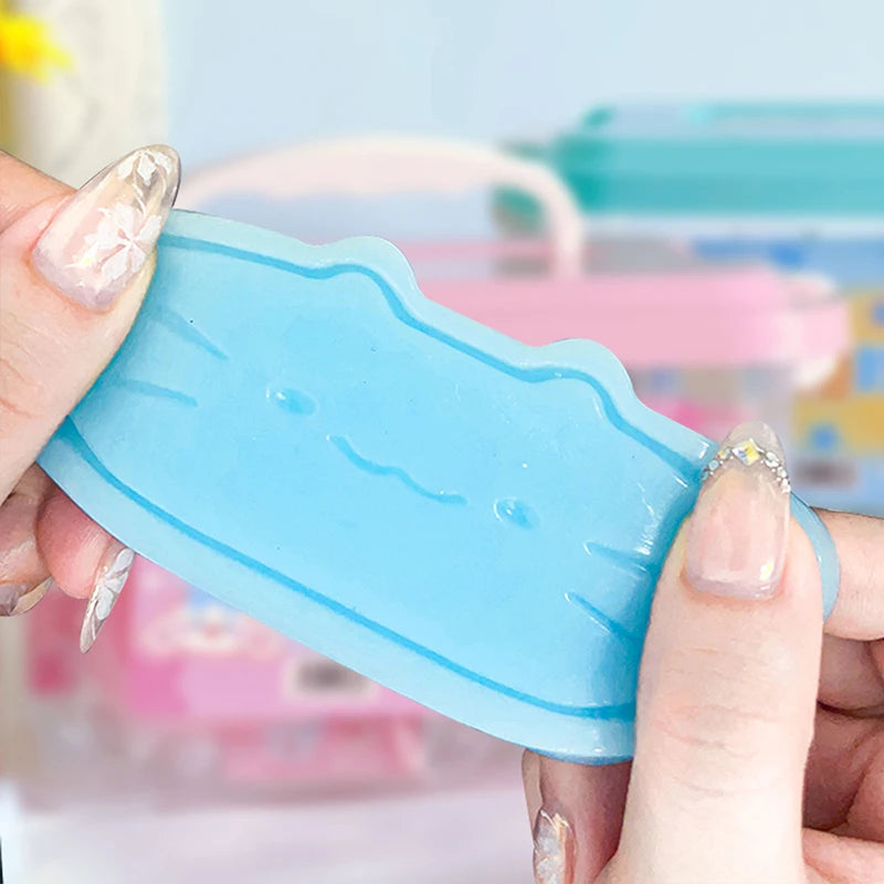 A hand holds a light blue squishy stress-relief toy shaped like a cat and cheese.