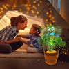 Une femme souriante et un enfant interagissent avec un jouet cactus dansant interactif éclairé par des guirlandes lumineuses.