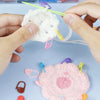 Hands are holding a white yarn pom-pom with colorful locking stitch markers for knitting and crochet