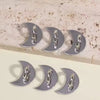 Silver decorative phone charm hooks with adhesive backing arranged on a light surface.