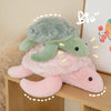 A soft, pink and green sea turtle plush toy resting on a wooden surface.