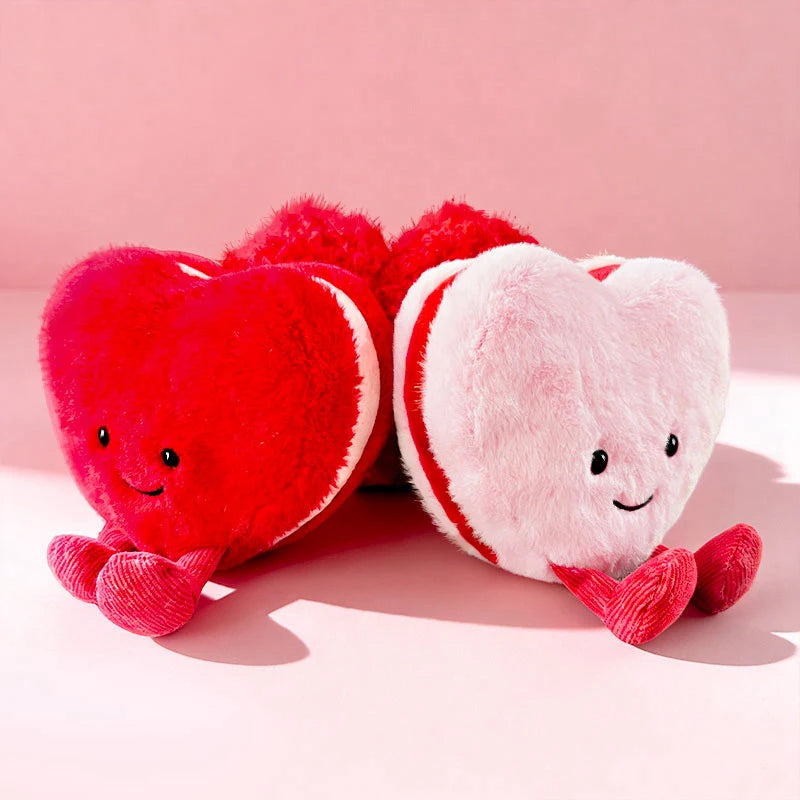 A pair of soft plush hearts, one red and one pink, resting on a light pink background.
