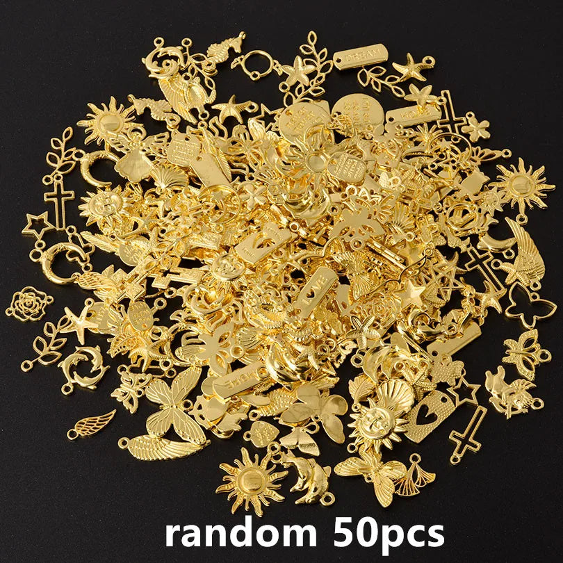 A pile of random gold metal charms and findings for DIY jewelry making