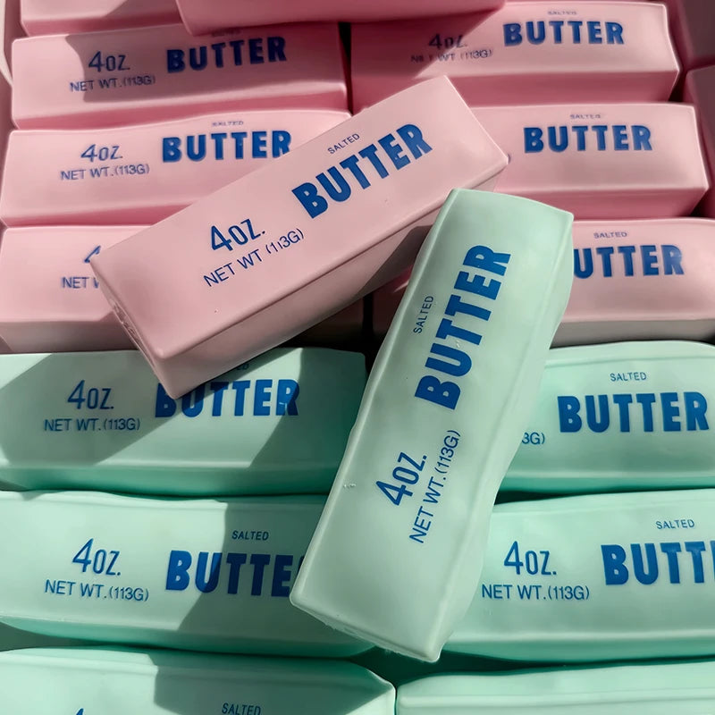 A collection of pink and white butter stick squishy fidget toys in various sizes and packaging.