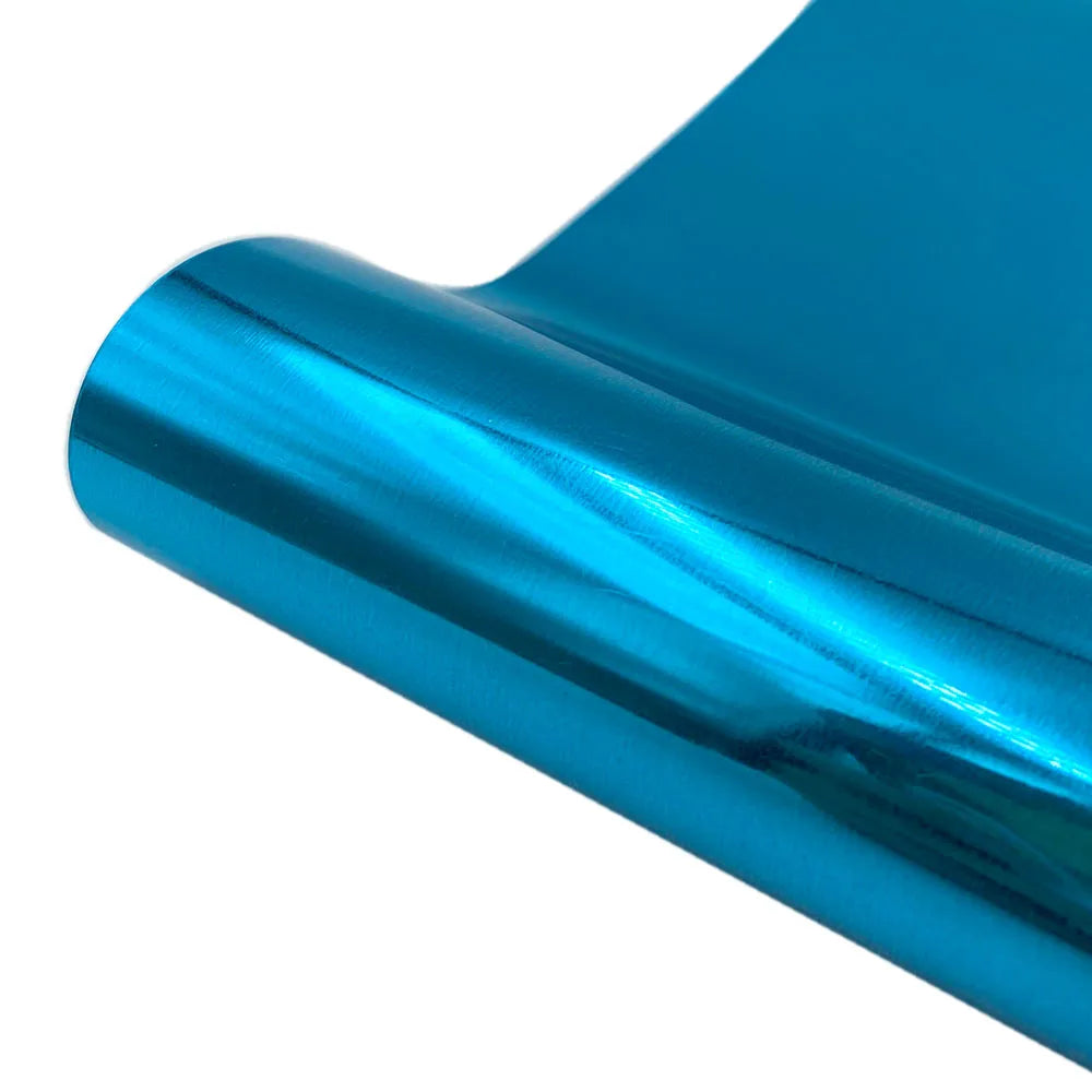 A close-up view of a shiny, teal blue heat transfer vinyl roll being rolled.