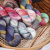 A bundle of hand-dyed Australian wool yarn in various gradient colors, including pinks, blues, greens, and purples, resting o